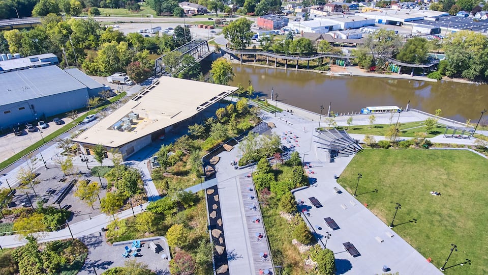 An aerial view of a parking lot with a bridge over a body of water, surrounded by greenery and buildings.