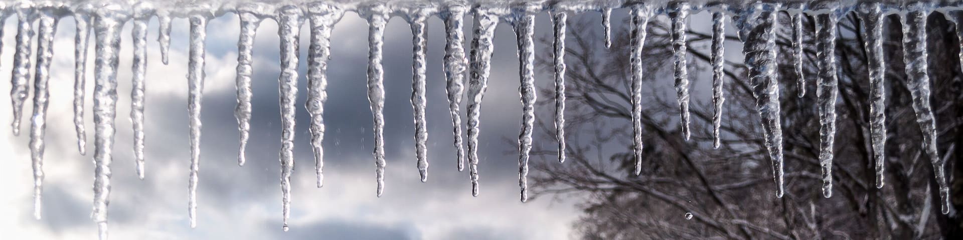 The white winter wonderland scenery in Londonderry, Vermont with snow covered trees, icicles and blue cloudy sky in the background on a cold day. Selective focus.