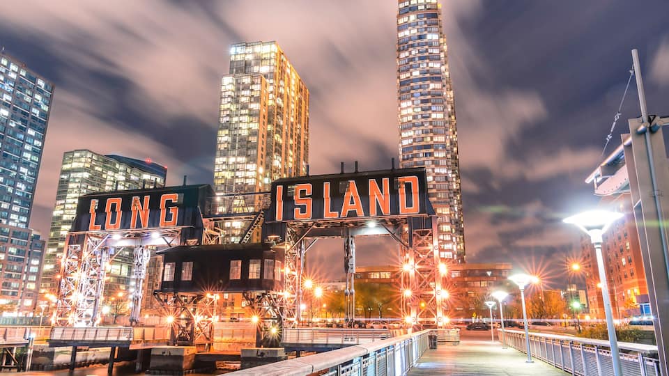 A cityscape with illuminated buildings and a sign that reads "LONG ISLAND."