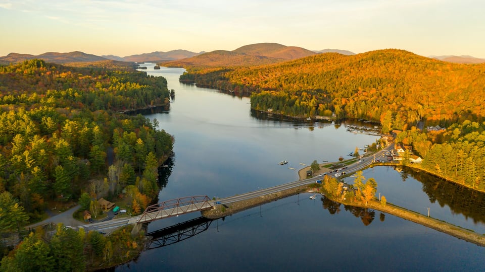 A river surrounded by autumn foliage, a bridge, and distant mountains.