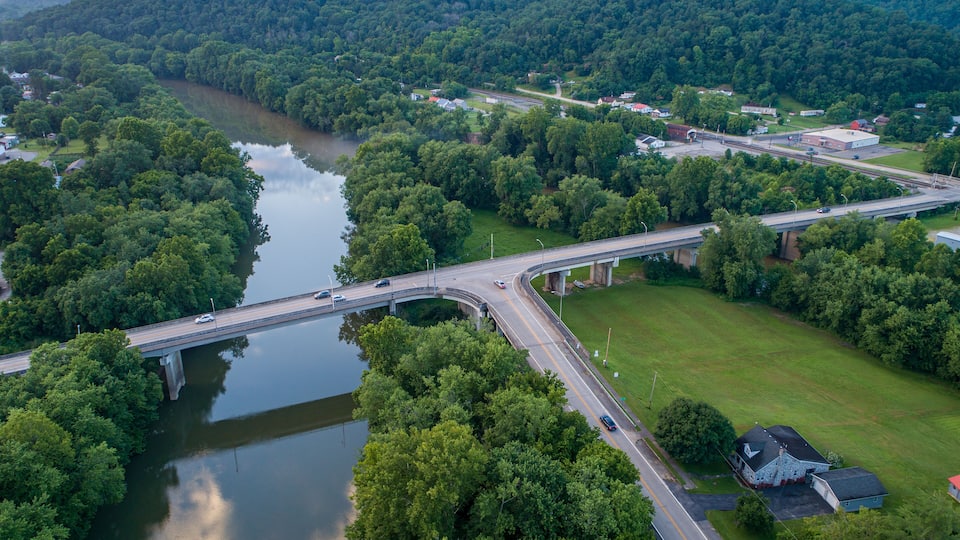 A bridge over a river with surrounding greenery and a highway.