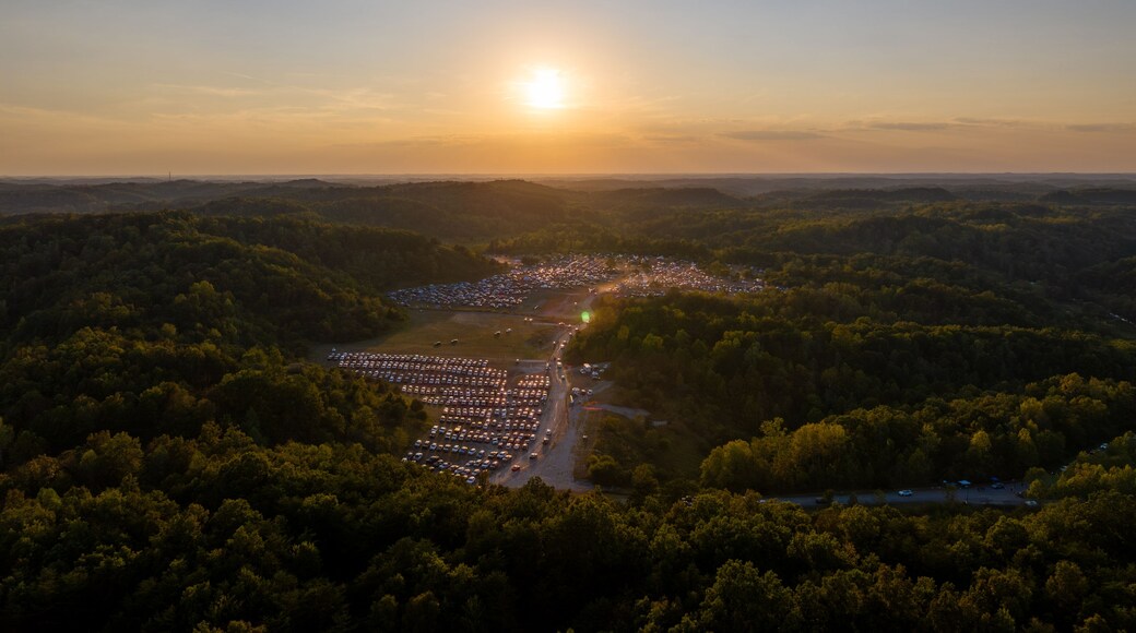 A sunset over a densely wooded area with a parking lot and a small town.