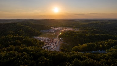 A sunset over a densely wooded area with a parking lot and a small town.