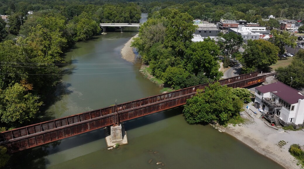 Aerial view of the Little Miami River winding through verdant trees, crossed by a rusty bridge near Loveland, Ohio, United States.