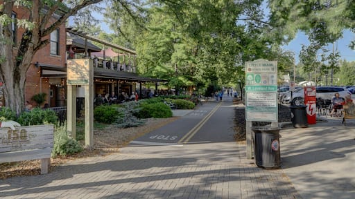 View of a brick building with a restaurant and people dining outside under the trees, beside a pathway for pedestrians, Loveland, Ohio, United States.