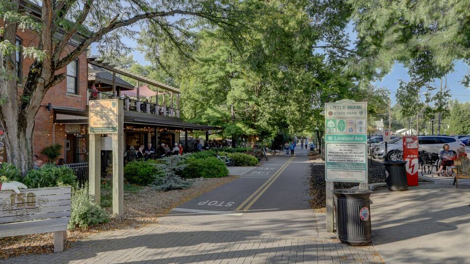 A street with a pedestrian crossing, a Little Miami State Park sign, and a W. Loveland Ave sign.