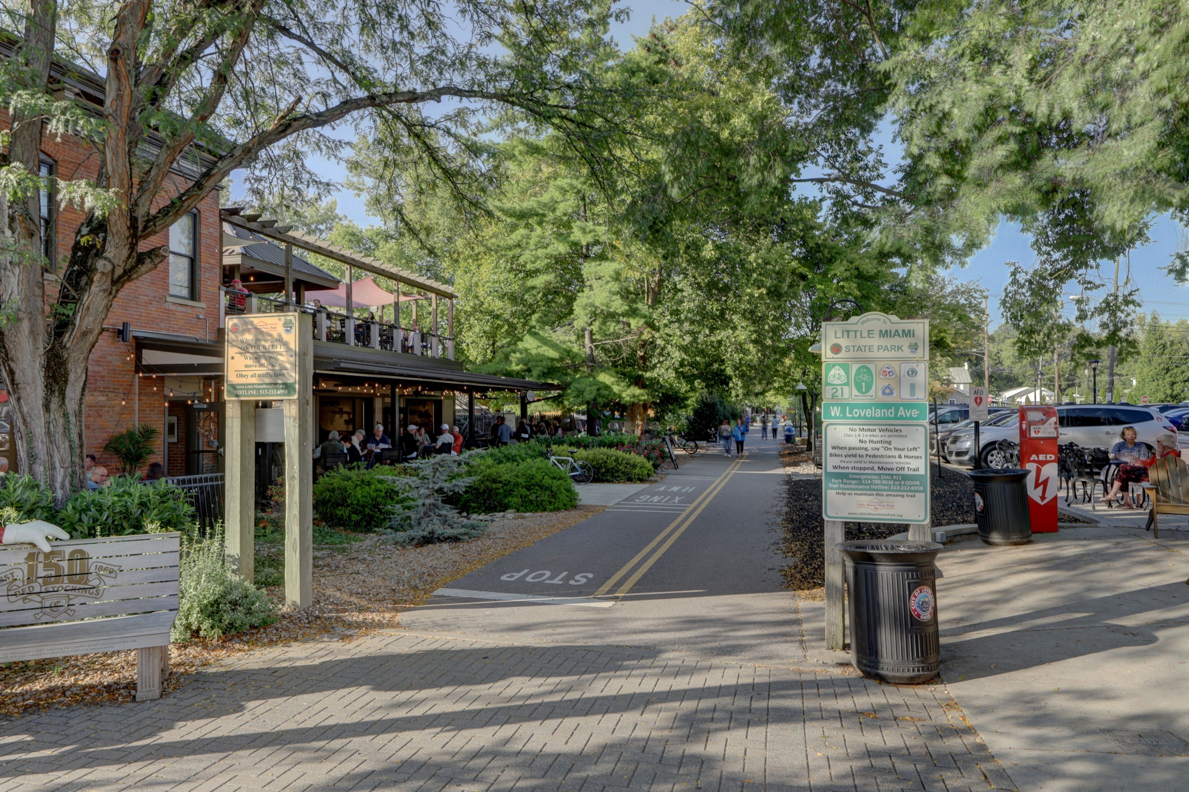 A street with a pedestrian crossing, a Little Miami State Park sign, and a W. Loveland Ave sign.