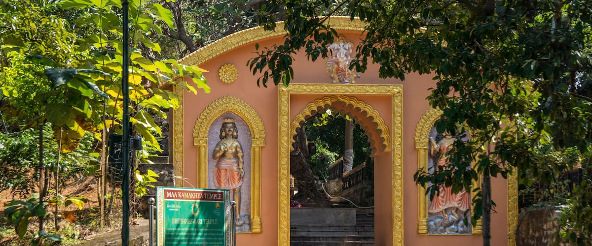 A temple entrance with a sign, steps, and statues.