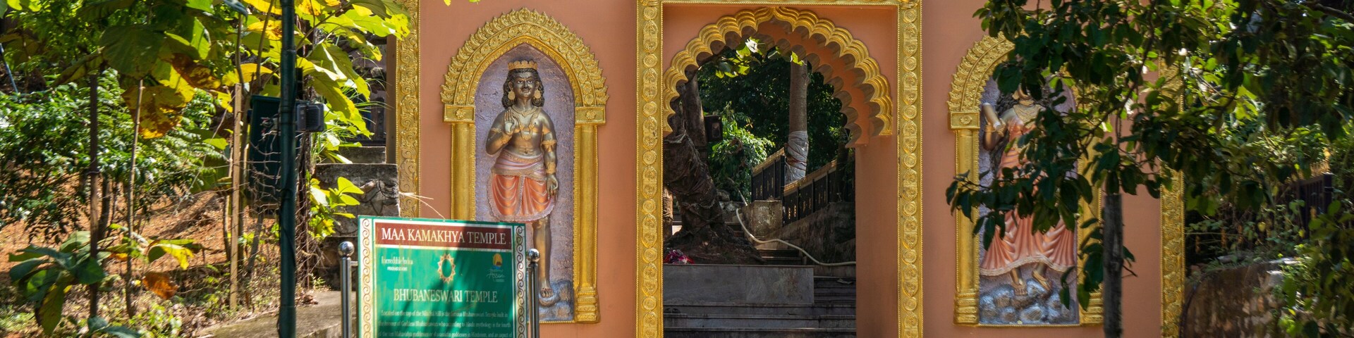 A temple entrance with a sign, steps, and statues.