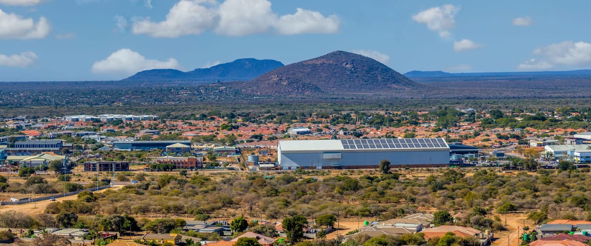 A town with a prominent mountain in the background, surrounded by sparse vegetation and residential buildings.