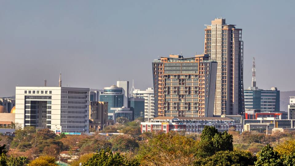 A cityscape with a prominent high-rise building, a mix of modern and traditional architecture, and a clear sky.