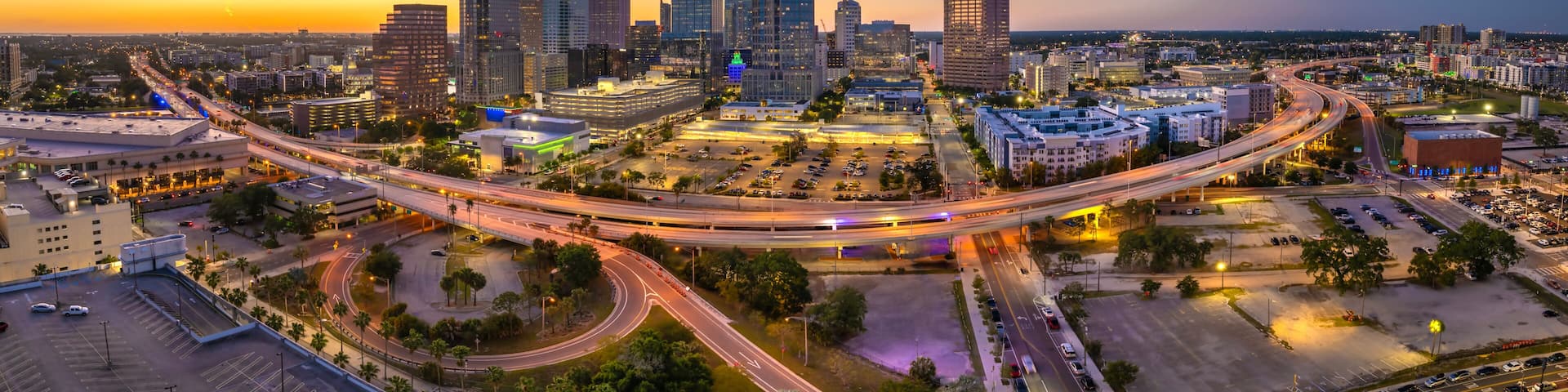 Night urban landscape of downtown district of Tampa in Florida, USA. American city skyline with brightly illuminated high commercial buildings and high speed highway road