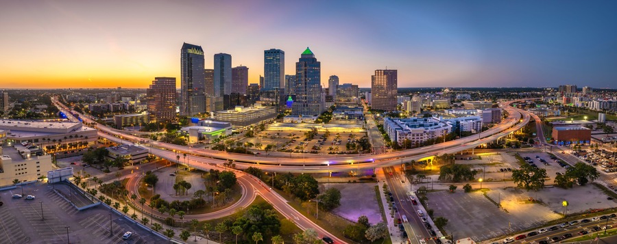 Night urban landscape of downtown district of Tampa in Florida, USA. American city skyline with brightly illuminated high commercial buildings and high speed highway road