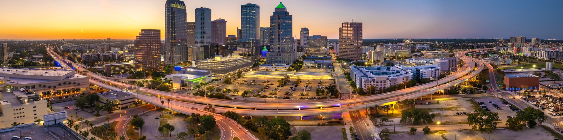 Night urban landscape of downtown district of Tampa in Florida, USA. American city skyline with brightly illuminated high commercial buildings and high speed highway road