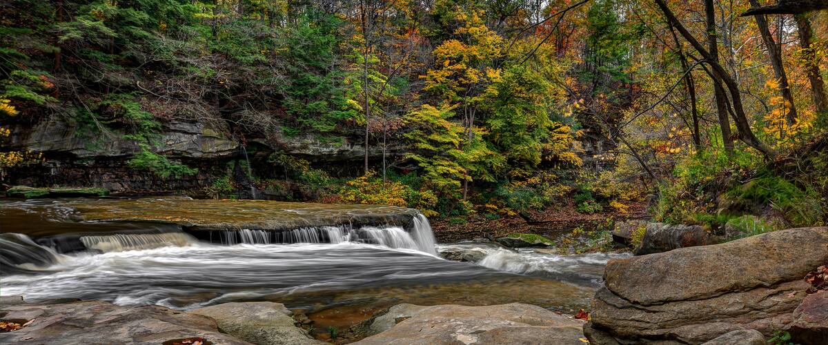 A waterfall in a forest with autumn foliage.