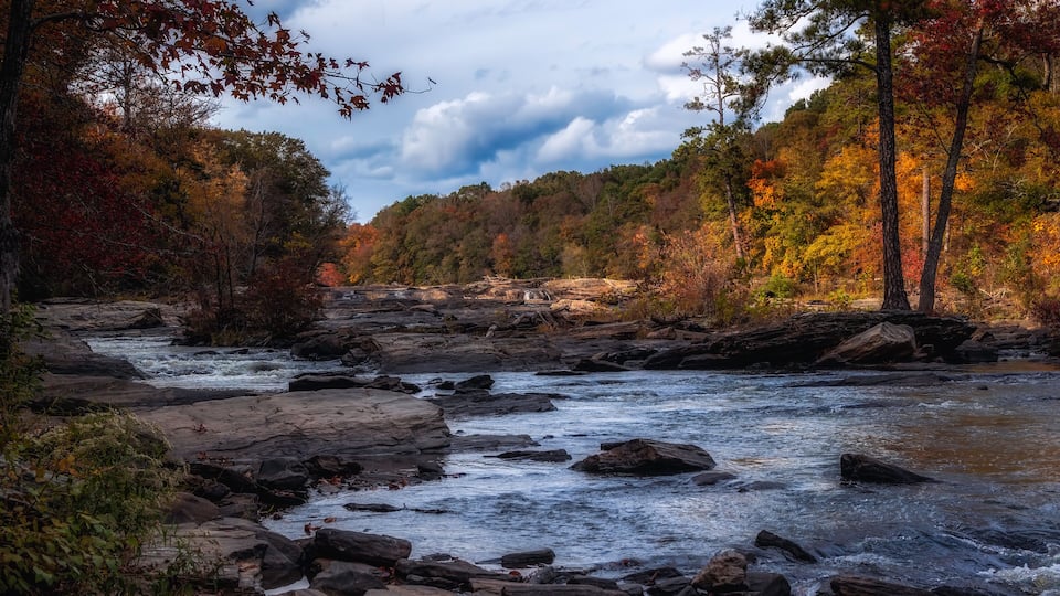 A river flowing through a rocky landscape with autumn-colored trees.