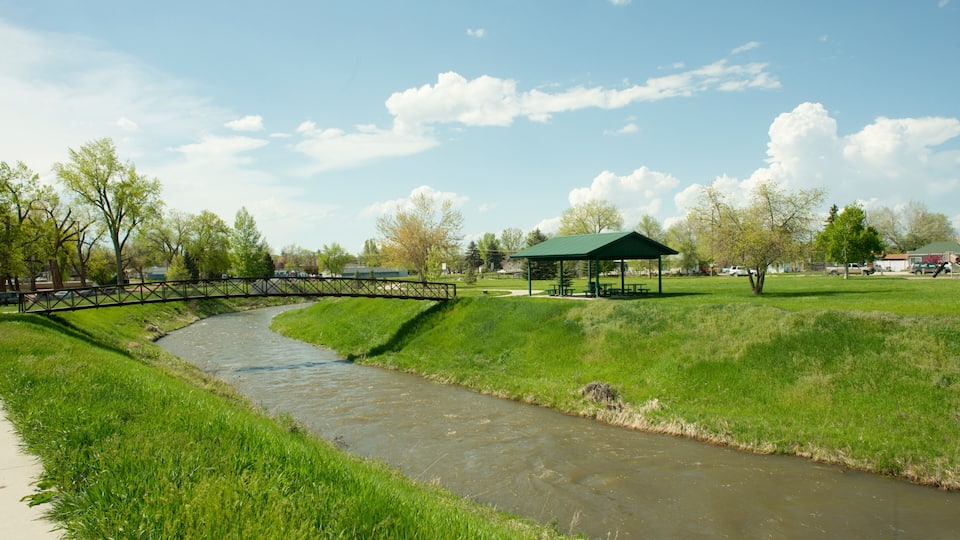 A river flowing through a park with a bridge, picnic tables, and a gazebo.