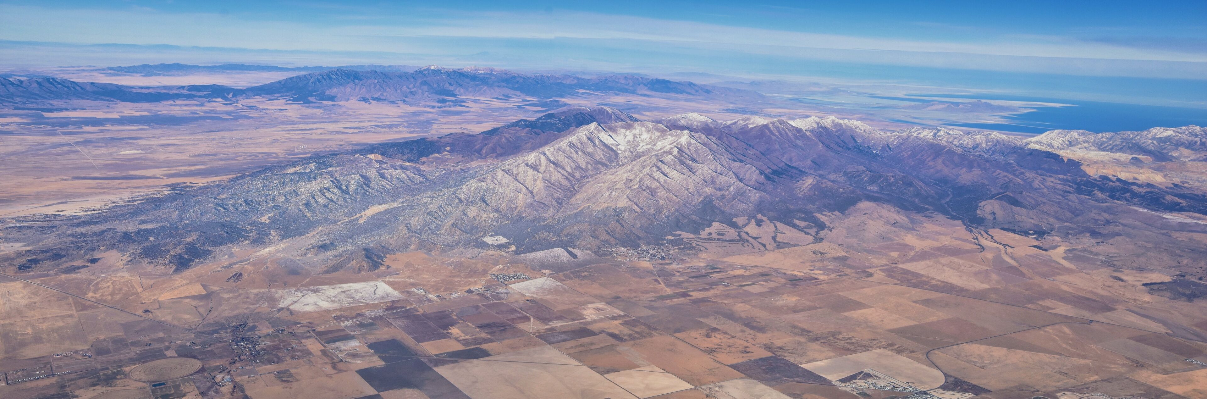 A mountainous landscape with snow-capped peaks and arid fields.