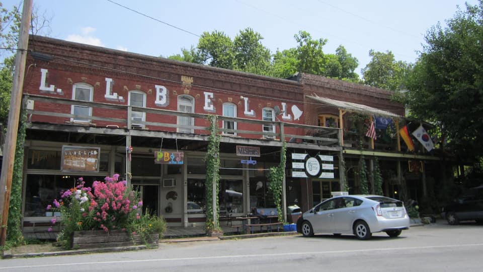 A historic building with 'LIBERTY' on the facade, a vintage car parked in front, and various signs including 'VISIONS' and 'DENTAL'.