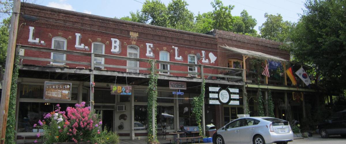 A historic building with 'LIBERTY' on the facade, a vintage car parked in front, and various signs including 'VISIONS' and 'DENTAL'.