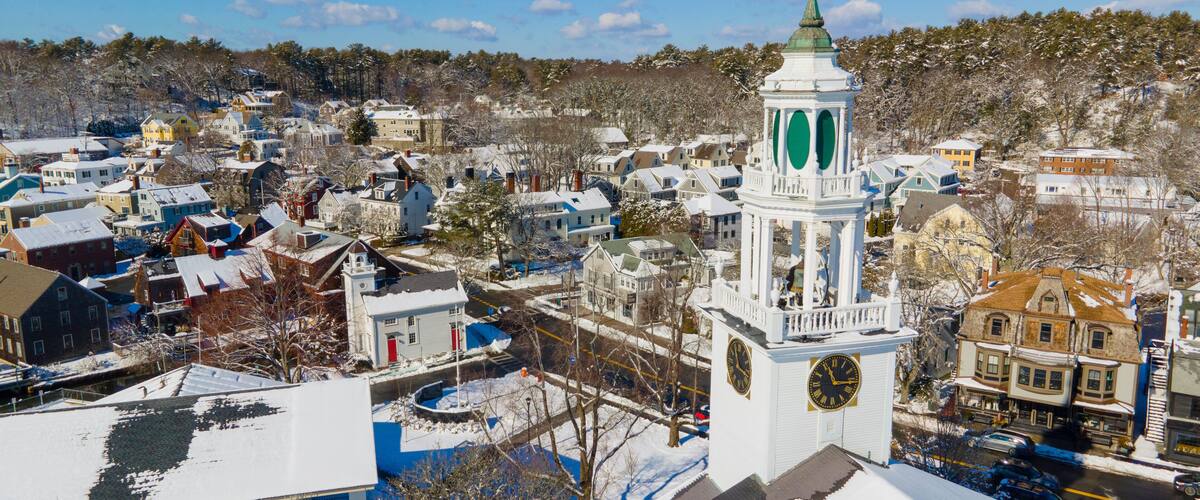 A snow-covered town with a prominent clock tower and a clear blue sky.