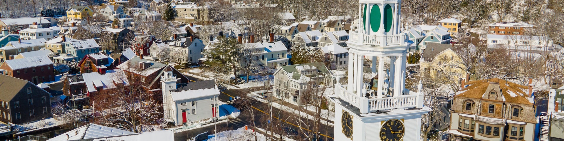 A snow-covered town with a prominent clock tower and a clear blue sky.