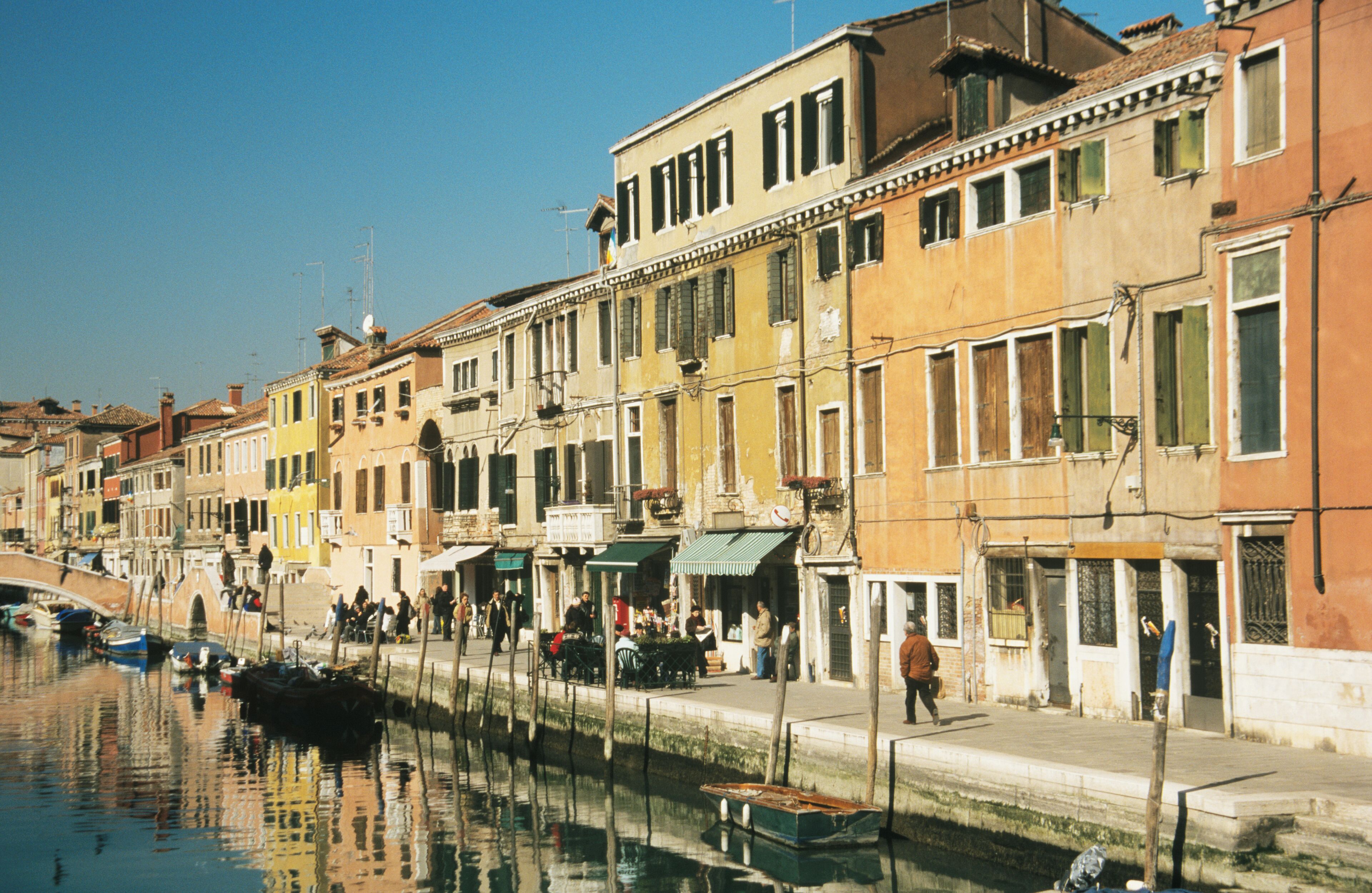 A canal with boats, a bridge, and colorful buildings along the water.