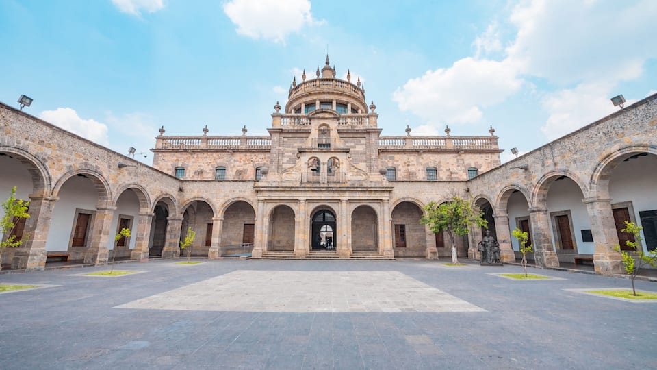A historic building with a central dome and arched walkways.
