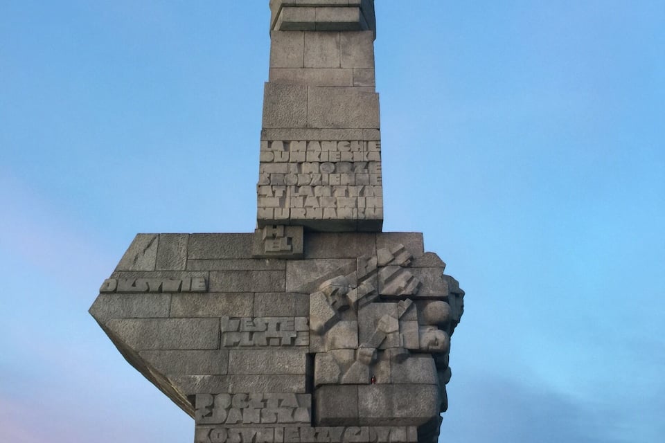 Un gran monumento de piedra con inscripciones y una figura empuñando una espada.