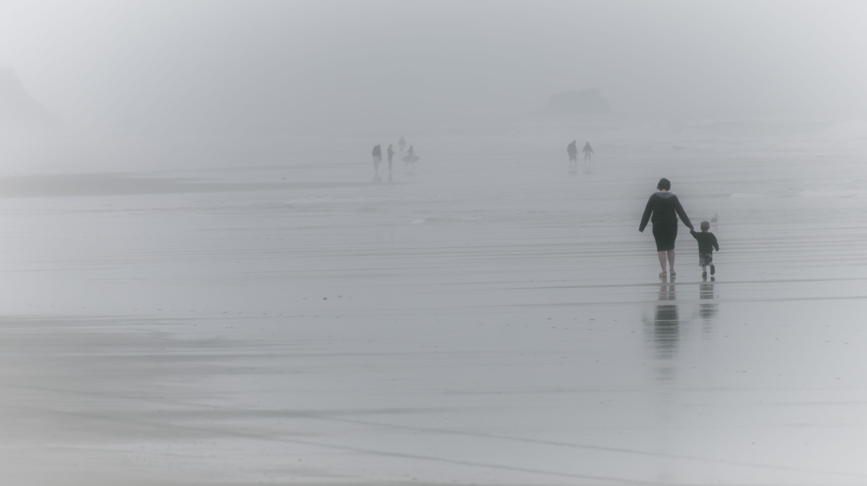 Una playa brumosa con gente caminando.