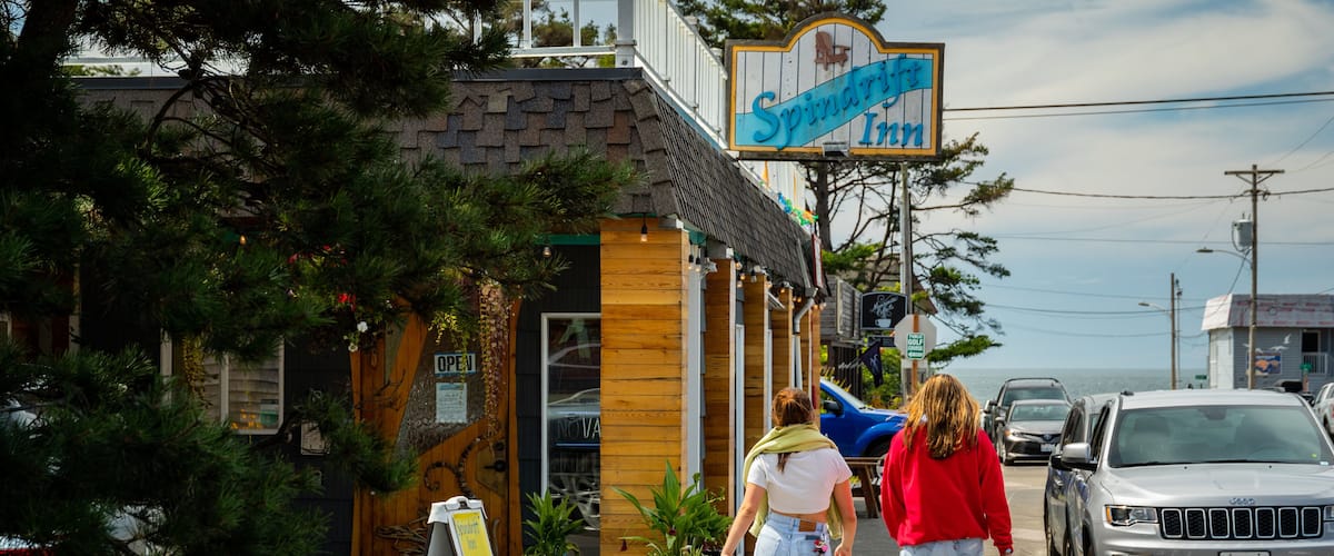 A building with a sign reading "Spindrift Inn" and a wooden door with a sign that says "OPEN".