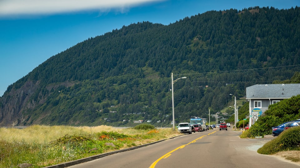 A road with cars parked on the side, a mountain in the background, and a building with a sign that reads "Sunset Speed 25".