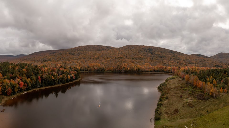 A lake surrounded by autumn-colored trees and hills.
