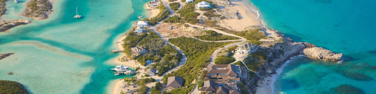 An aerial view of a coastal resort with clear turquoise waters, sandy beaches, and lush greenery.