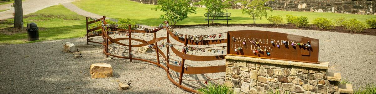 Savannah Rapids Love Locks area with a rustic building and greenery on a sunny day. Georgia, USA