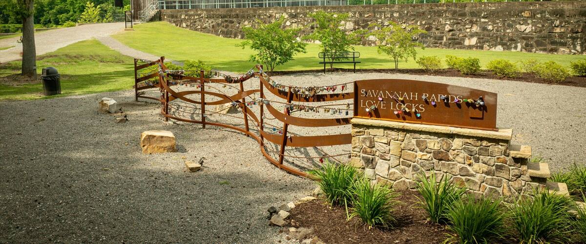 Savannah Rapids Love Locks area with a rustic building and greenery on a sunny day. Georgia, USA