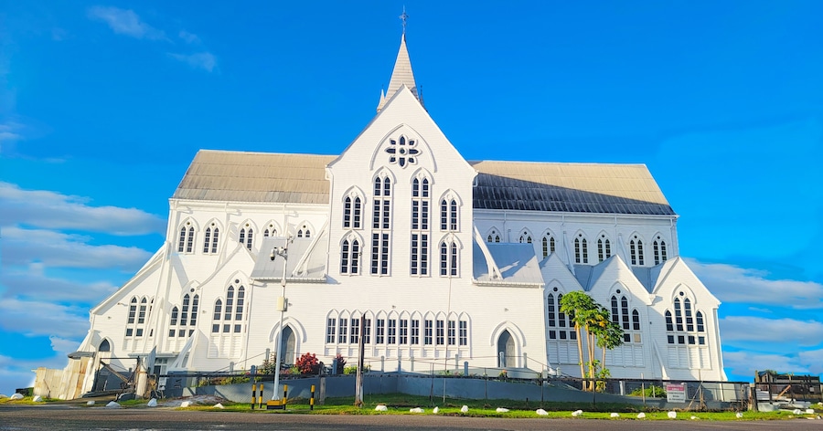 Uma igreja grande e branca, com um campanário pontudo e várias janelas em arco.