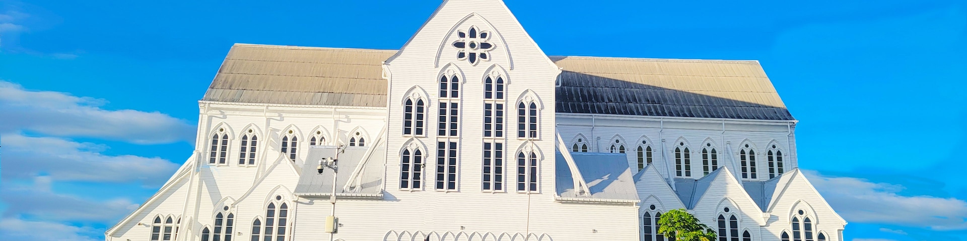 A large white church with a pointed steeple and multiple arched windows.