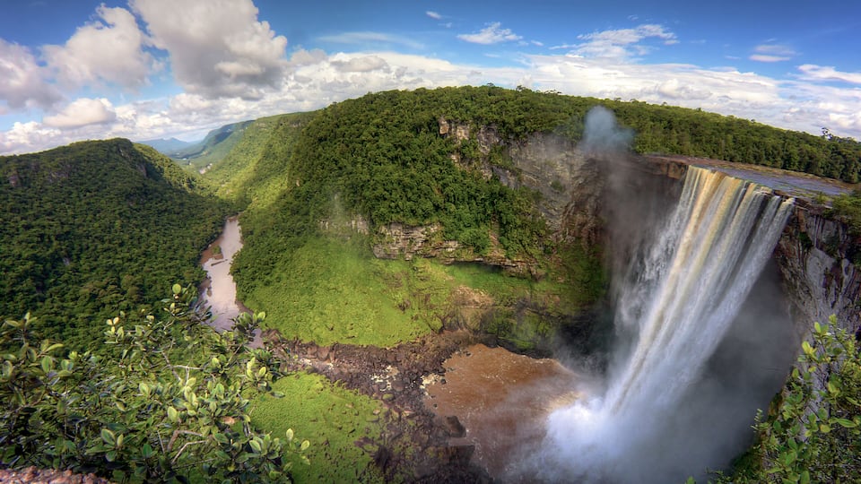 A waterfall cascading down a cliff surrounded by lush greenery.