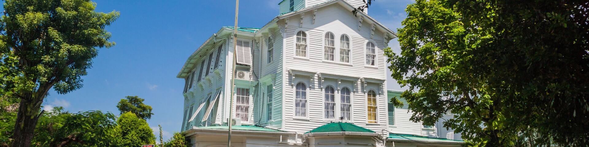 A white building with a green roof and a flagpole.