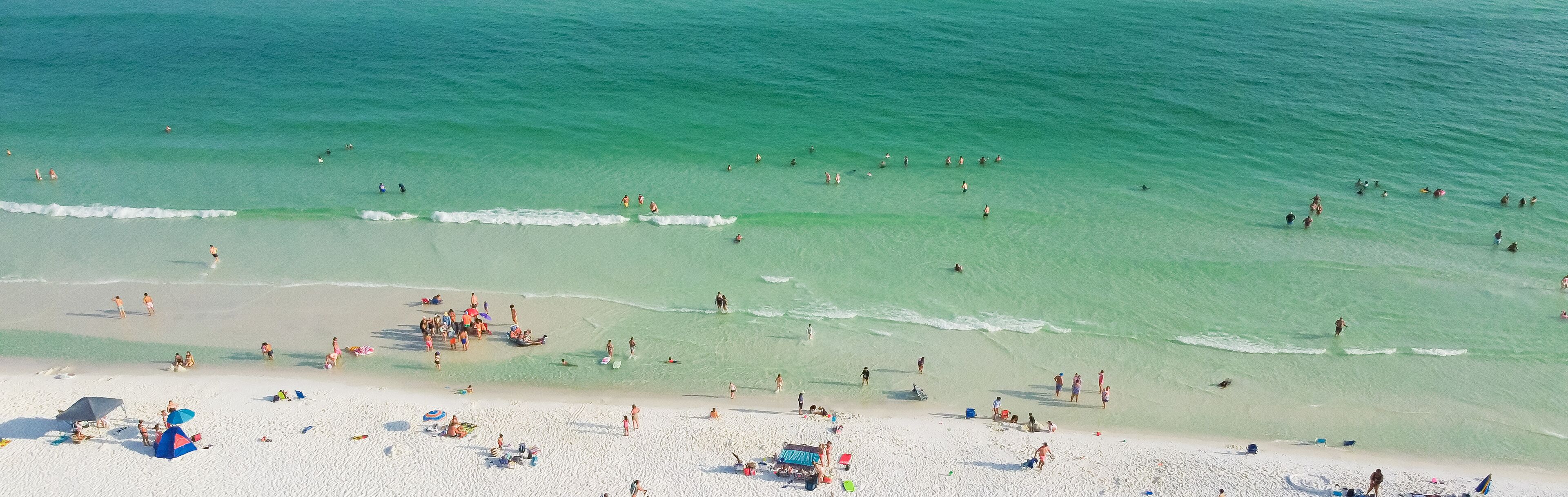 Panorama aerial view Destin beaches with crowded beach umbrella, people swimming relaxing on sugar-white sand beaches, turquoise water, gorgeous shade blue waves in South Walton, Florida, USA