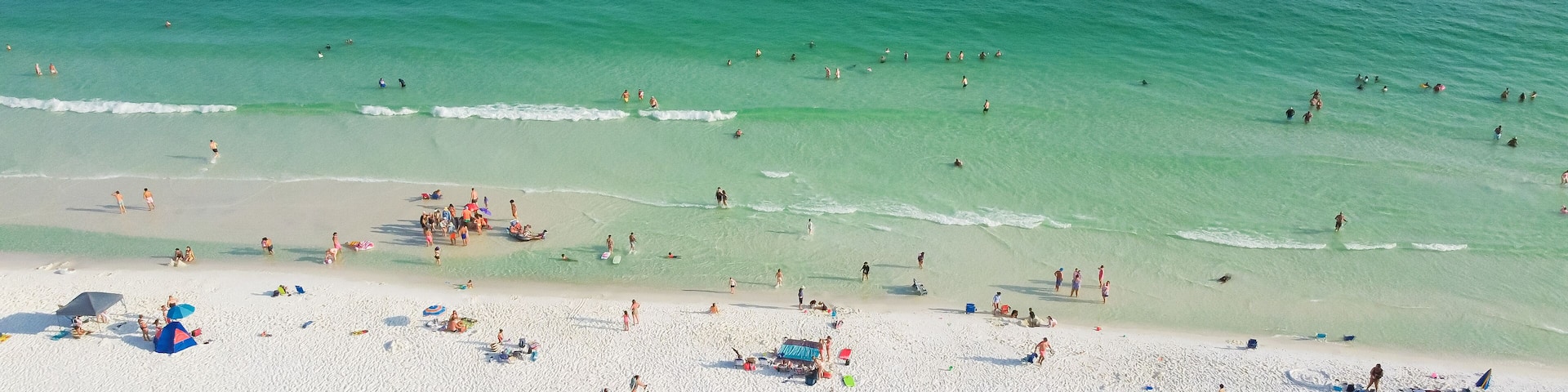 Panorama aerial view Destin beaches with crowded beach umbrella, people swimming relaxing on sugar-white sand beaches, turquoise water, gorgeous shade blue waves in South Walton, Florida, USA