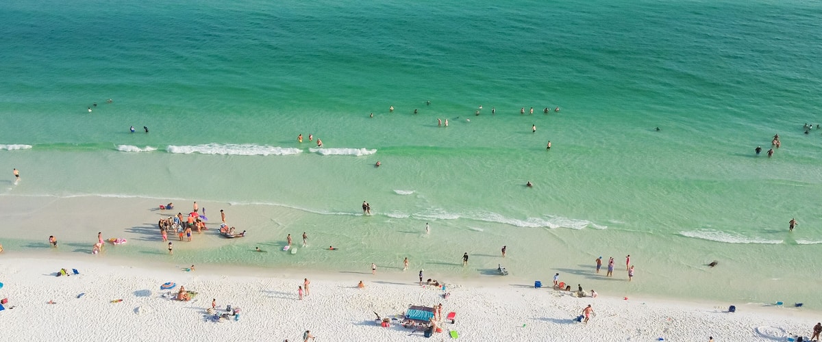 A crowded beach with people swimming and sunbathing.