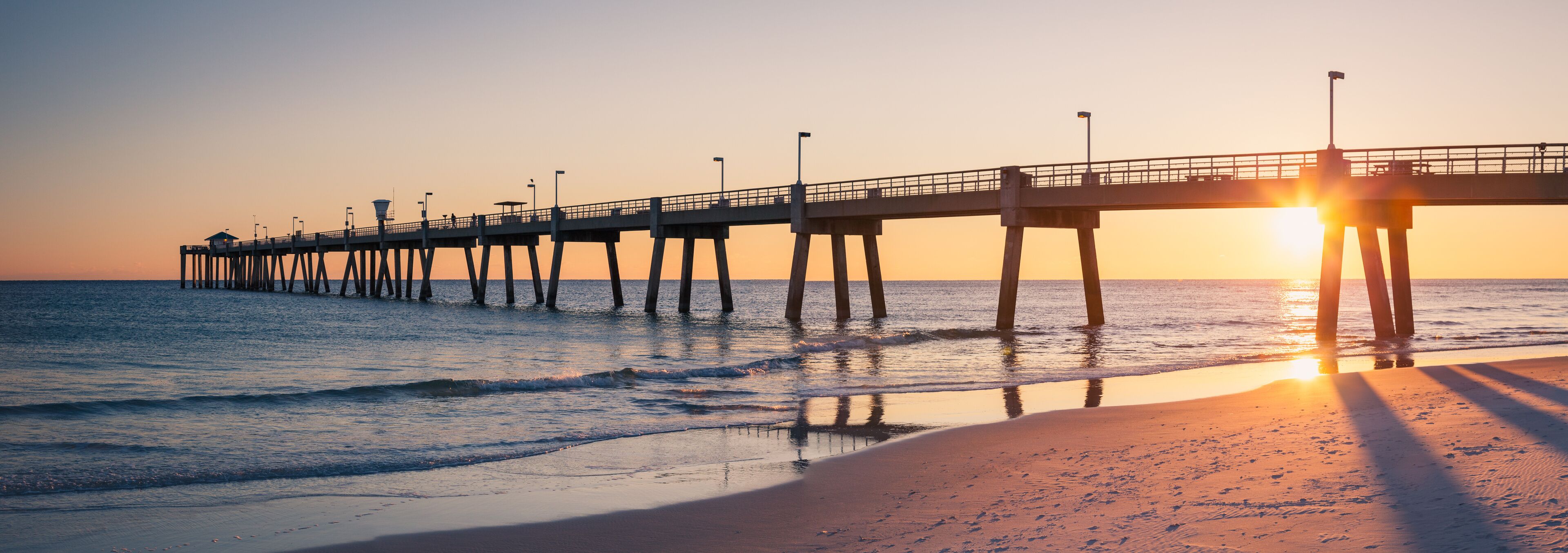 A pier extending into the ocean at sunset.