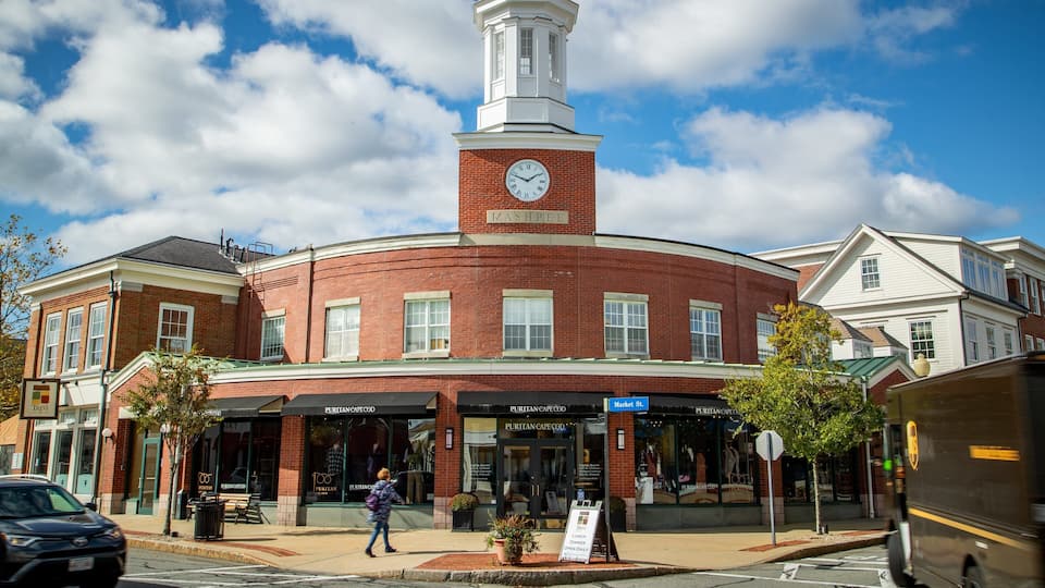 A historic building with a clock tower, named "MASHPIEE," and a sign for "PURITAN CAPE COD."
