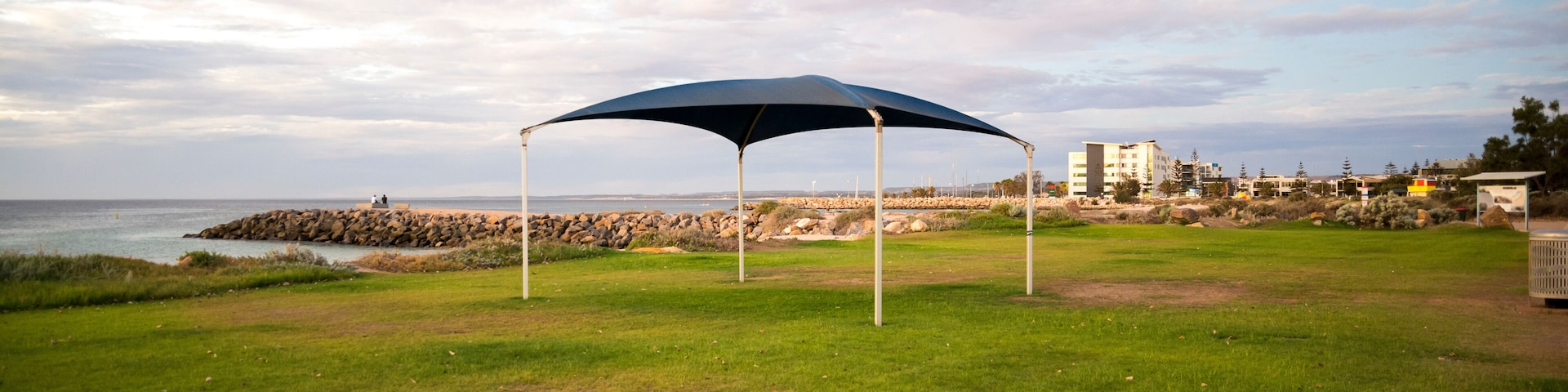 Blue shade sail on green lawn at beach foreshore with ocean view, Geraldton, Western Australia, 28 February 2023