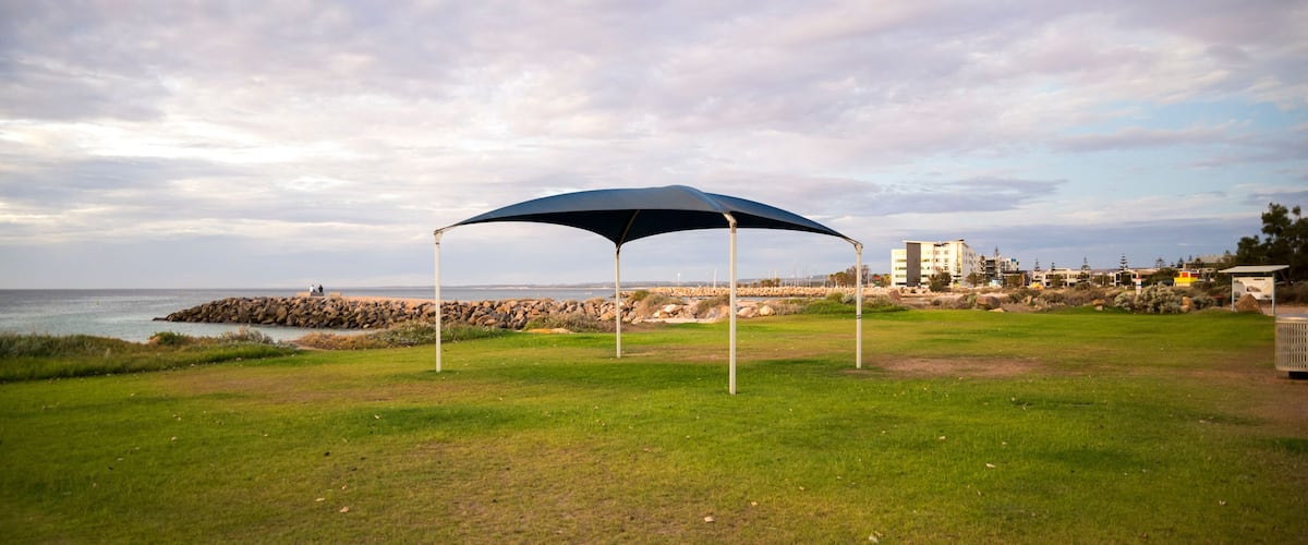 Blue shade sail on green lawn at beach foreshore with ocean view, Geraldton, Western Australia, 28 February 2023