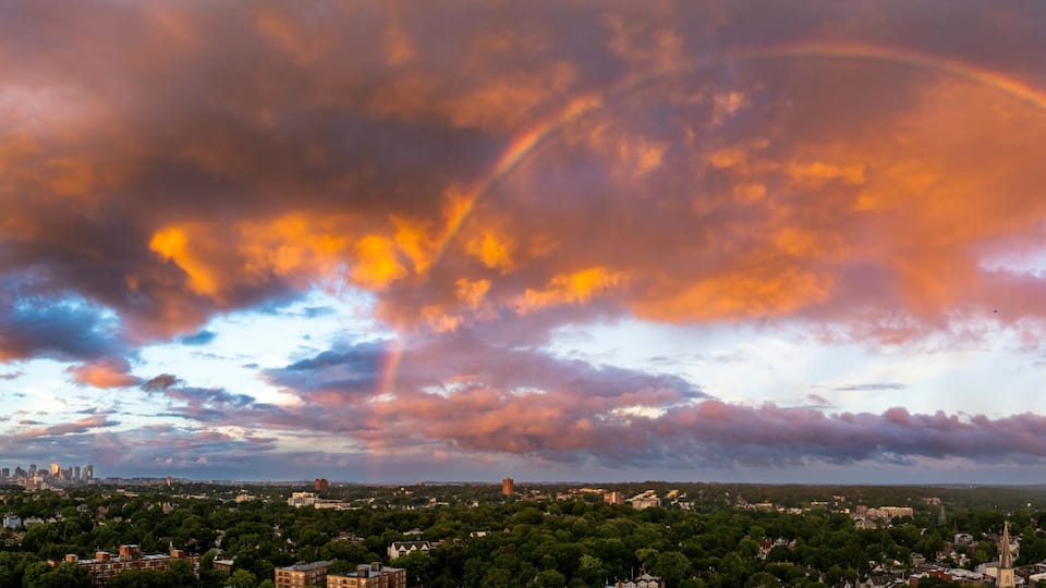 A cityscape with a rainbow and clouds.