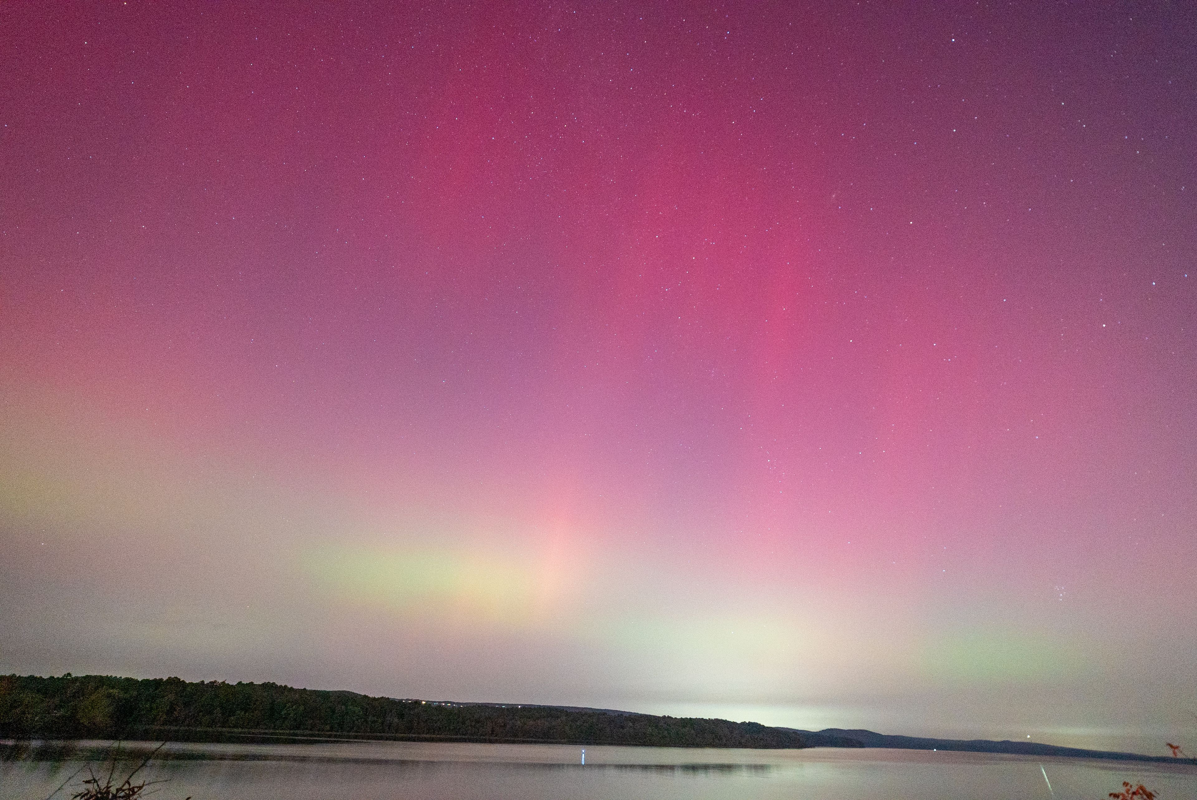 A night sky with a visible aurora display over a body of water.