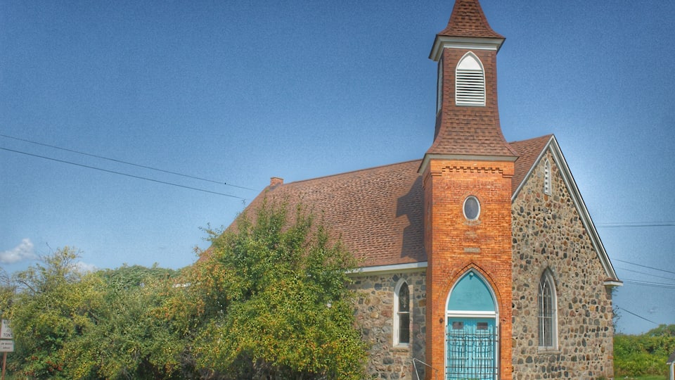 A church with a brick steeple and a blue door.